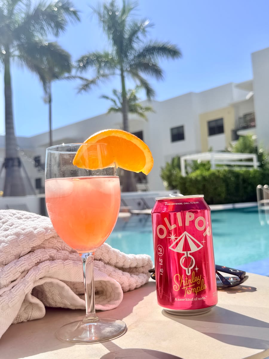 Olipop Shirley Temple can and a drink by the pool